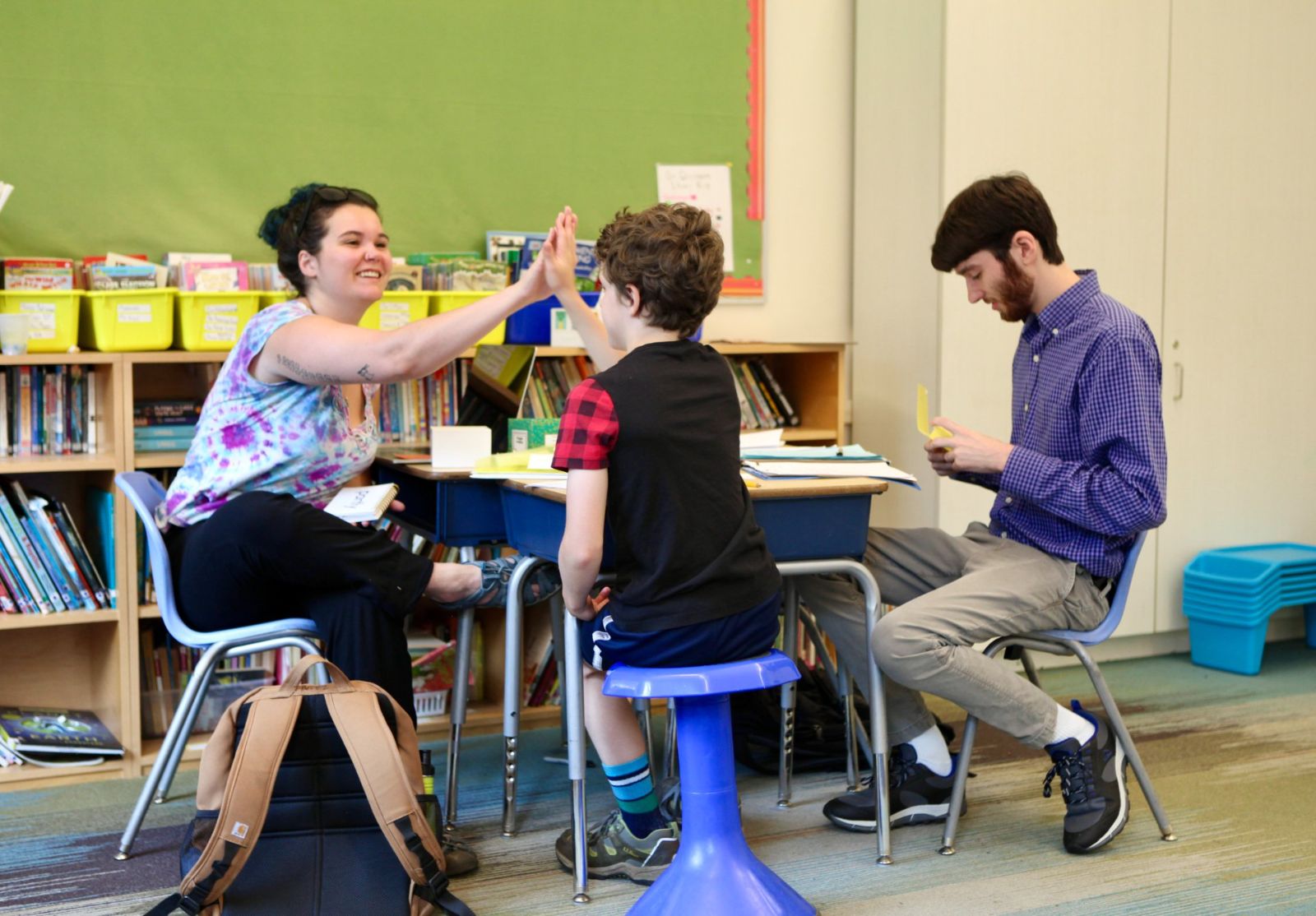 A tutor high-fiving a student across a desk during a one-on-one session