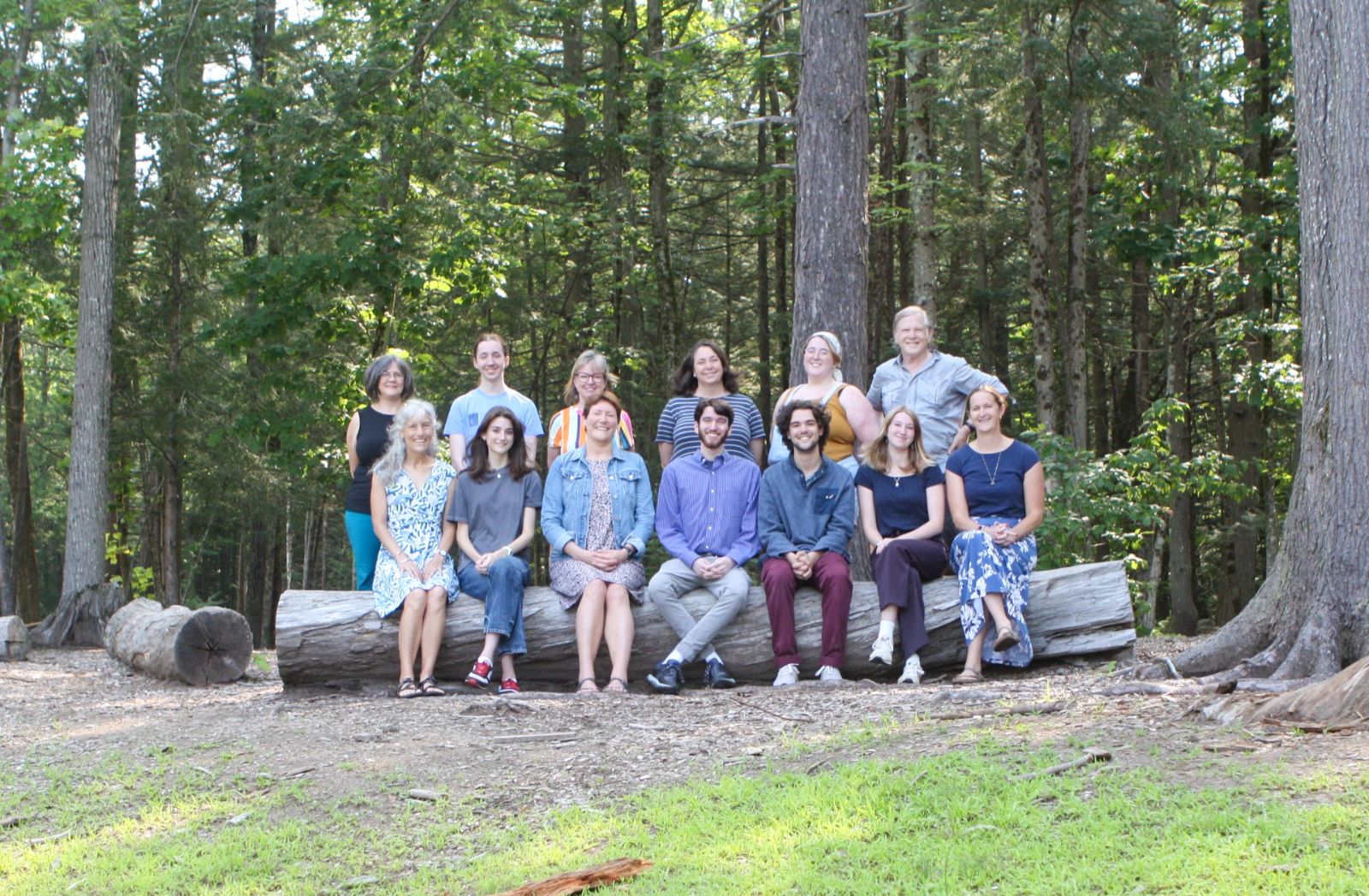 The Pine State Learning team seated on a log among pine trees